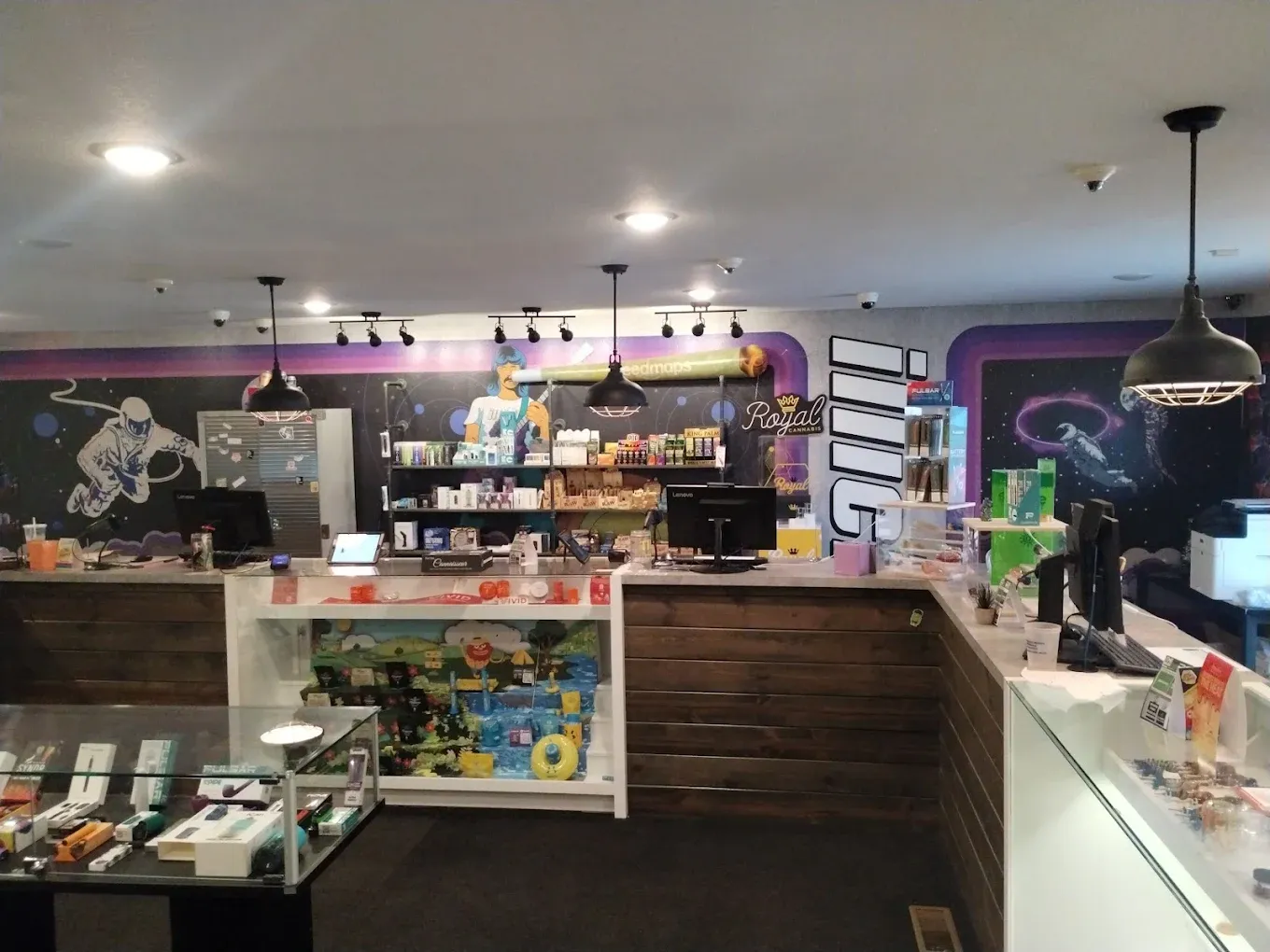 Interior view of cannabis dispensary with wooden counter, shelving displays, and purple lighting