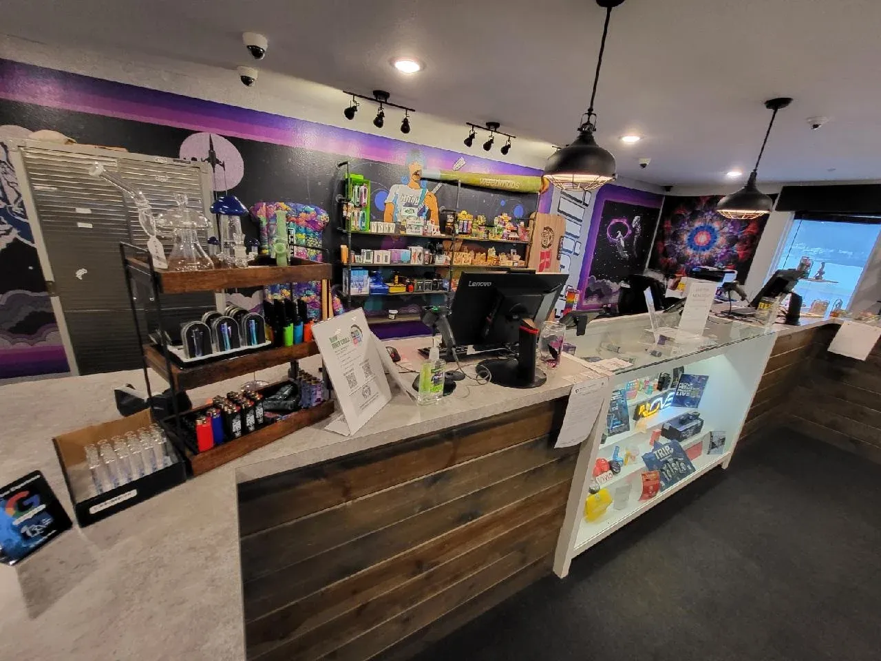 # Alt Text
Interior view of cannabis dispensary with wooden counter, shelving, and purple ambient lighting